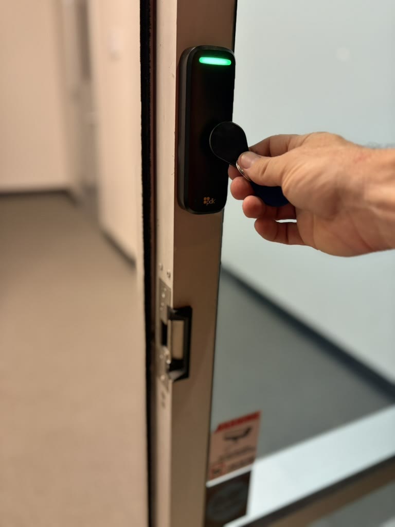 Key fob unlocking a glass office door with a new electric strike in the frame