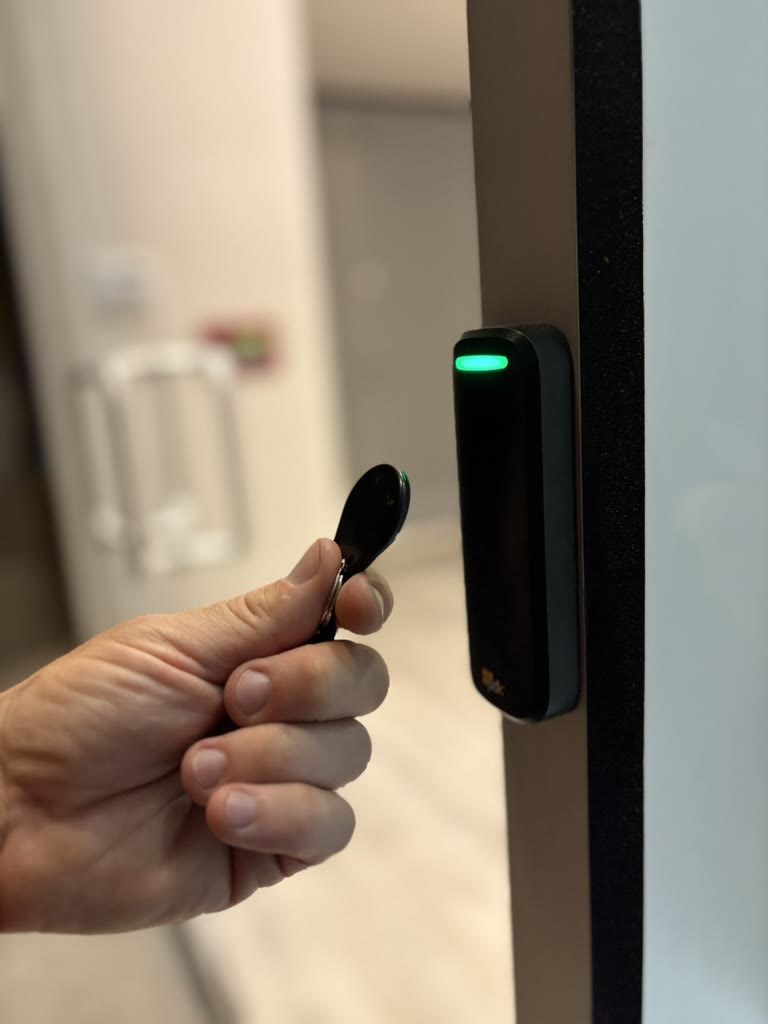 Presenting a key fob to a door reader glowing green at an office suite entrance