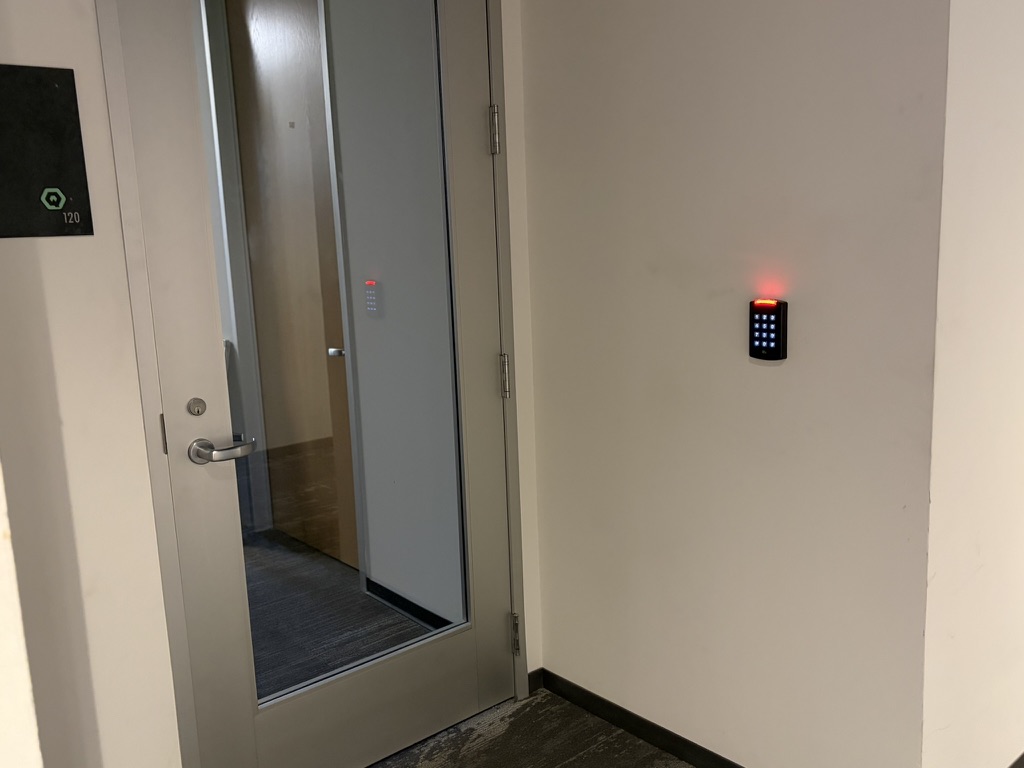 Keypad access reader mounted beside a glass office suite door